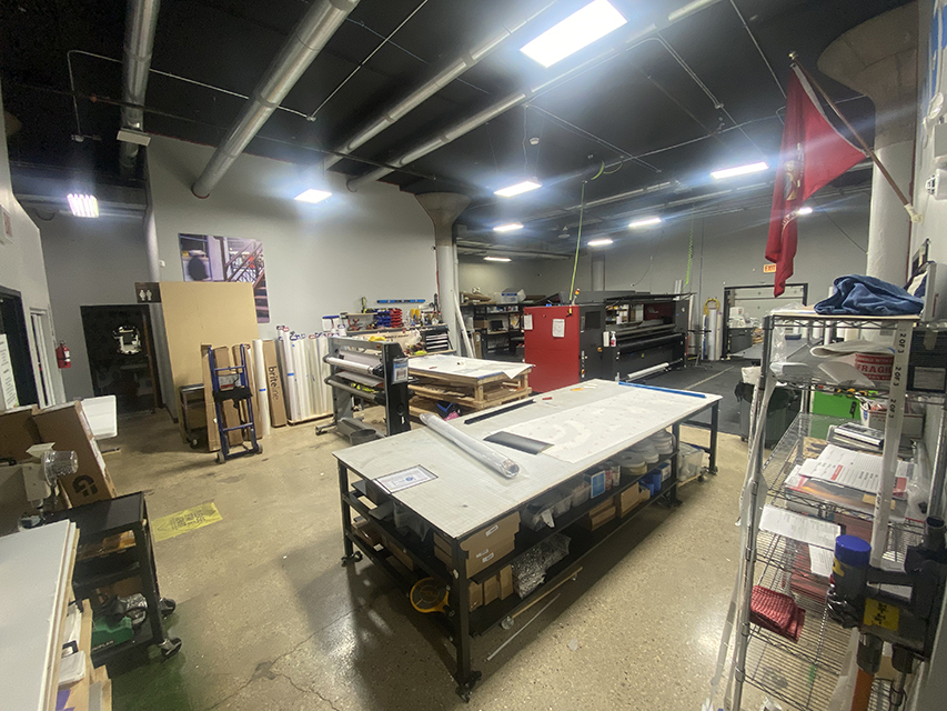 Large-format print shop with worktables and equipment.