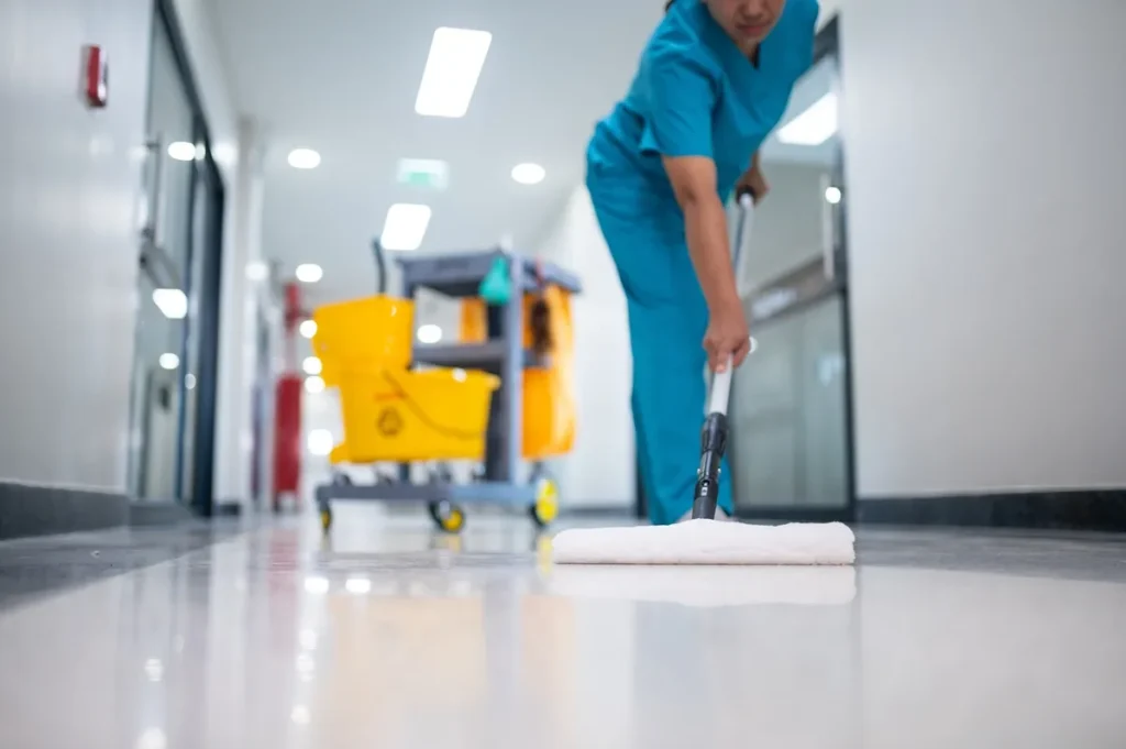 Janitor mopping hallway – “Janitor mopping a shiny hallway floor with a cleaning cart nearby.”
